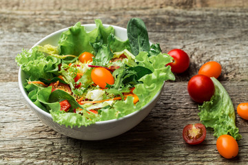 Salad with fresh vegetables - tomatoes, carrots, bell peppers and mixed greens - arugula, mesclun, mache.