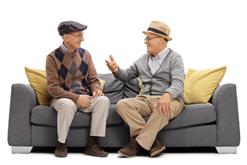 Two elderly men sitting on a sofa and talking