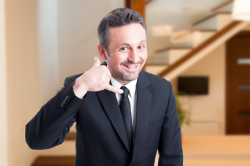 Cheerful real estate agent doing a call gesture