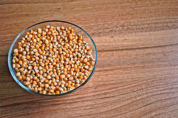 Popcorn kernels in a bowl on a wooden table