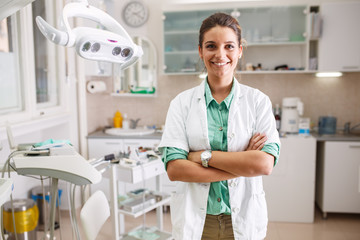 Portrait of female dentist. She's standing in her dentist office.	