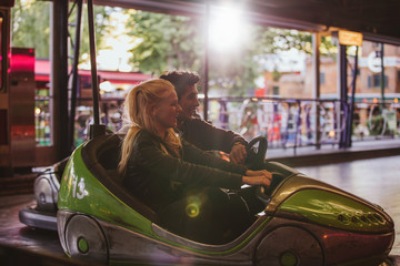Happy young couple driving a bumper car at amusement park