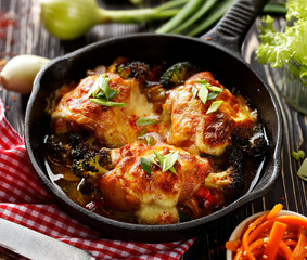 Roasted  chicken thighs  stuffed with vegetables, baked with mozzarella cheese on a black cast iron pan