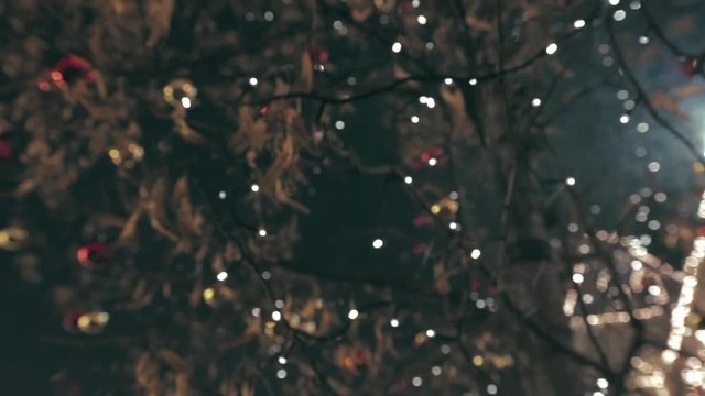 Christmas street decoration. Building, trees in garlands. Red and yellow decorative balls hanging on the trees against background with illuminated building. Beautiful Christmas Balls.