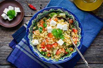 Bowl of healthy and delicious fresh tabbouleh salad with bulgur, pomegranate and feta cheese