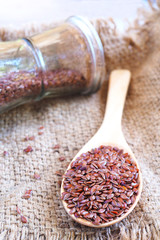 Close up of wooden spoon of flax seeds on a sackcloth. 