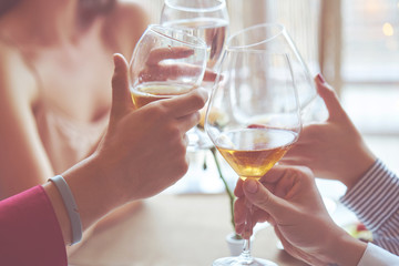 Clinking glasses of champagne in hands on bright lights background