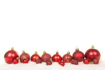 Row of red christmas ball decorations in the snow on a white background