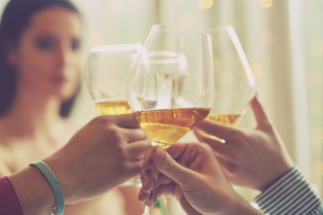 Clinking glasses of champagne in hands on bright lights background
