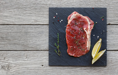 Raw beef steak on dark wooden table background, top view