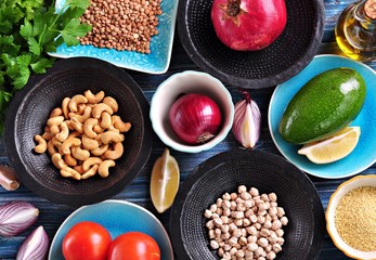 Ingredients of middle eastern cuisine - chickpeas, lentils, couscous, pomegranate, red onion, tomato, avocado, cashew nuts, parsley, olive oil and garlic.