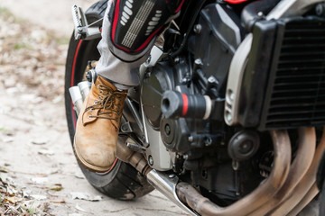 Fototapeta premium Biker sitting on motorcycle, close-up view on legs.