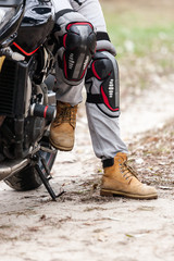 Biker sitting on motorcycle, close-up view on legs.