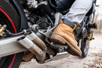 Biker sitting on motorcycle, close-up view on legs.