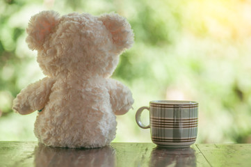 Teddy bear with coffee cup on wooden table