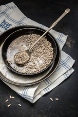 Sonnenblumenkerne in einer Schale aus Metall und einem Esslöffel auf einem alten rostigen Metalluntergrund