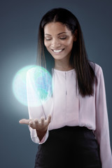 Mixed race woman smiling at spinning glowing globe hologram
