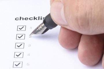Businessman checking mark on checklist with marker over white