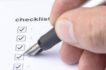Businessman checking mark on checklist with marker over white