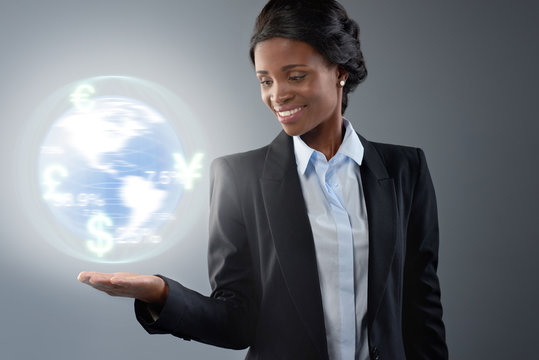 Businesswoman in suit smiling at spinning glowing globe hologram