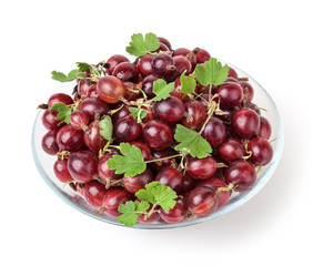 Red gooseberries with green leaves in glass bowl isolated on white background with clipping path