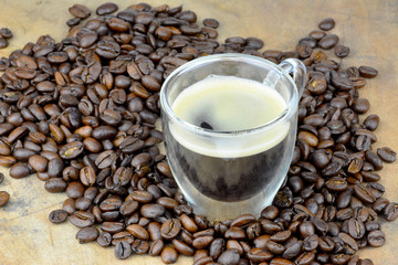 Espresso mit Kaffeebohnen auf einem Holztisch