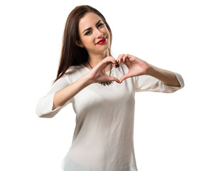 Naklejka premium Pretty young girl making a heart with her hands