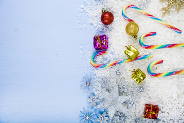 Silver decorative snowflakes and snow on a blue wooden backgroun