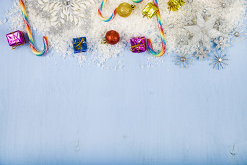 Silver decorative snowflakes and snow on a blue wooden backgroun