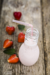 Smoothies and ripe strawberry on a wooden table. Milk drink with