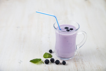 Smoothie or yogurt with blueberries on a wooden table. Delicious