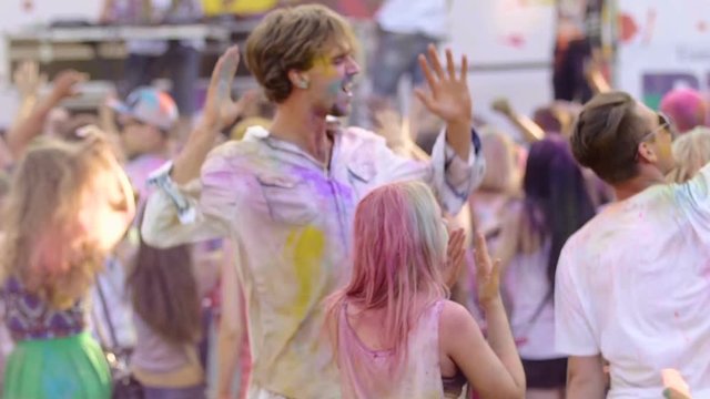 Wild crowd going crazy at cool festival, friends covered in paint taking selfie