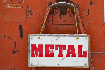 sign with word Metal over white hanging on old orange bin