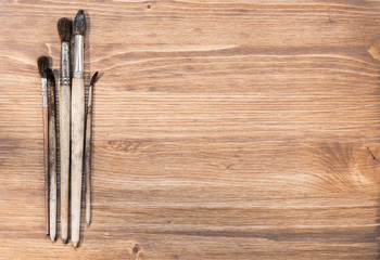 Four painted brushes on wooden background