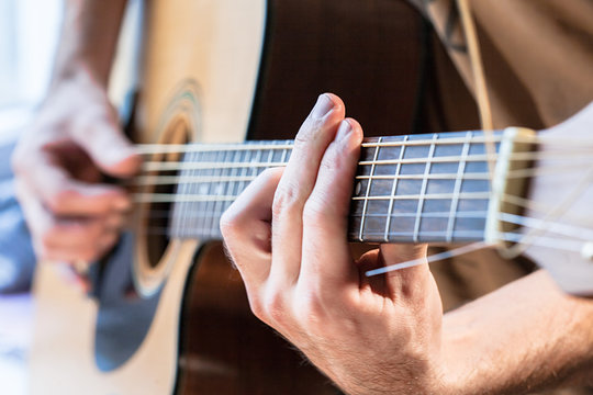 Man's hand playing acoustic guitar