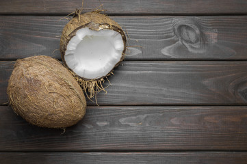 Coconut with coconut oil in jar on wooden background