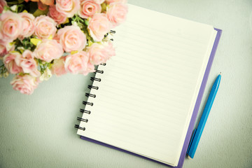 Naklejka premium Empty notebook with pen and flower. Abstract background.