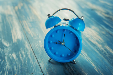 blue clock on antique rustic wood background.