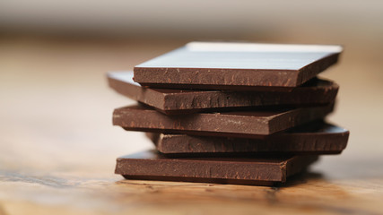 stacked pieces of chocolate bar on wooden table, shallow focus