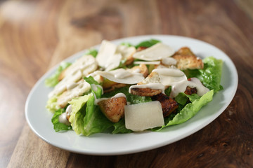 angle shot of caesar salad with chicken on old wooden table, shallow focus