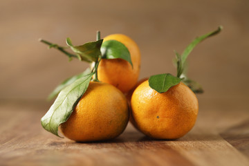 organic fresh tangerines with leaves on wooden table, shallow focus