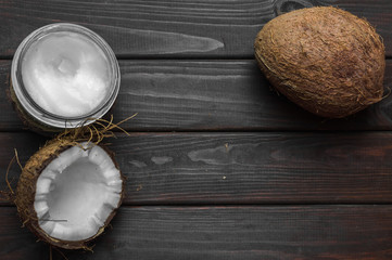 Obraz na płótnie Canvas Coconut with coconut oil in jar on wooden background