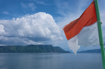 Flag of Indonesia flying with cloudy landscape at the background