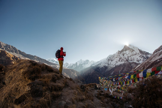 Tourist man watching and taking mobile photo of sunrise over the sacred mountain Machapuchare from Annapurna Base Camp in Himalaya Mountains