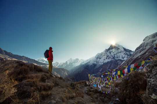 Tourist man watching sunrise over the sacred mountain Machapuchare from Annapurna Base Camp in Himalaya Mountains