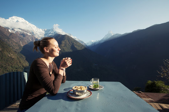 Young woman enjoy morning and drink coffee or tea in beautiful Himalaya mountains on hiking trip. Inspirational landscape, Nepal