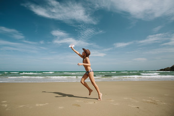 Fototapeta na wymiar Young Boy throwing paper plane, running on sea beach and enjoy summer day. Blue sky, beautiful beach shore, freedom