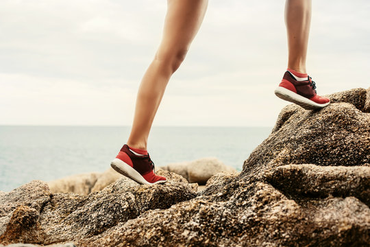 Woman running sport feet. Trail running marathon, fitness legs on rock and healthy summer lifestyle