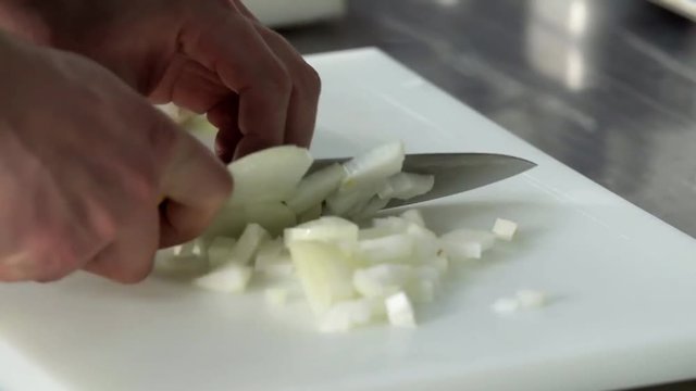 Chef hand cutting with knife onion 4k close up video. Chopped Food preparing in restaurant kitchen
