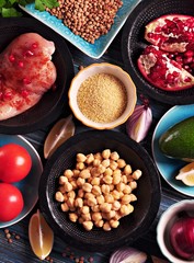 Ingredients of middle eastern cuisine - chickpeas, lentils, couscous, pomegranate, red onion, tomato, avocado,  chicken breast, paprika, parsley, olive oil and garlic.